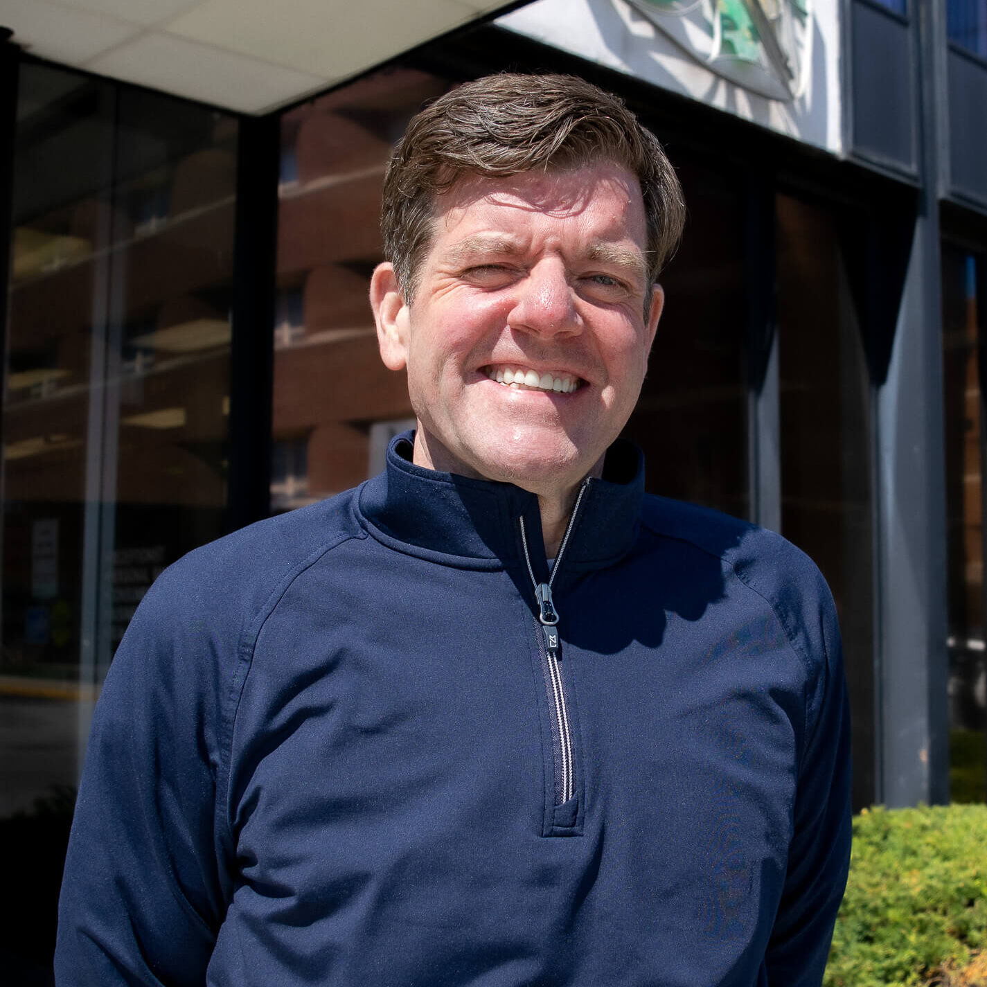 Man smiling in front of building